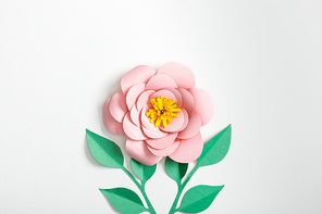 top view of pink paper flower and green plants on grey background