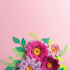 top view of colorful paper flowers and green plants with leaves on pink background