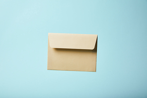 beige and blank envelope on blue background with copy space