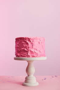delicious pink birthday cake on cake stand isolated on pink