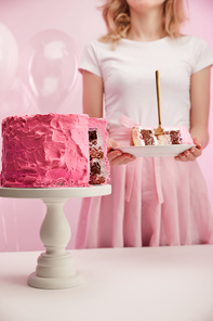selective focus of delicious birthday cake on cake stand near woman on pink