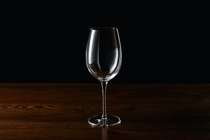 Empty wine glass on wooden surface isolated on black