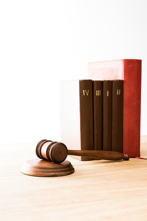 brown gavel near row of red and brown books on wooden table isolated on white