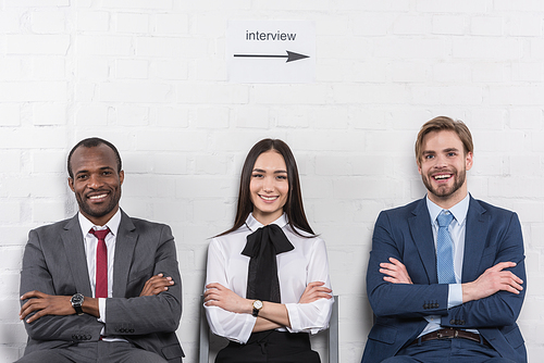 portrait of smiling multicultural business people with arms crossed waiting for job interview