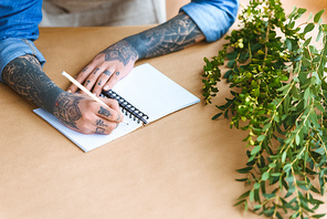 cropped shot of florist taking notes at workplace