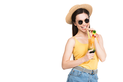 smiling girl in sunglasses and hat drinking cocktail, isolated on white