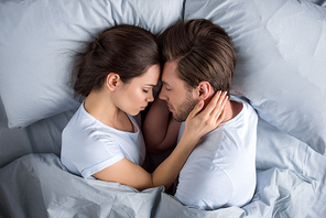 Young couple embracing while sleeping in bed