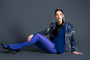 Slim woman in blue pantyhose and raincoat lying on dark background