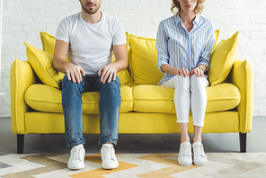 Cropped image of young couple sitting on couch in modern room
