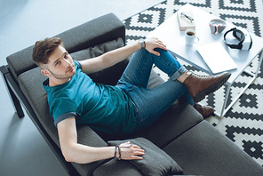 high angle view of handsome young man sitting on couch and 