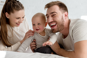 beautiful smiling parents with little son on bed