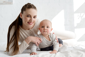 smiling mother with little baby boy lying on bed