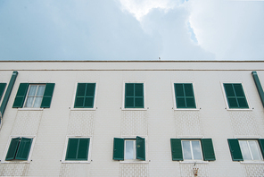 bottom view of european building with shuttered windows in front of cloudy sky, Anzio, Italy