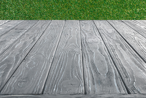 surface of grey wooden planks on green grass background