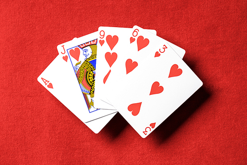 top view of red poker table and unfolded playing cards with hearts suit