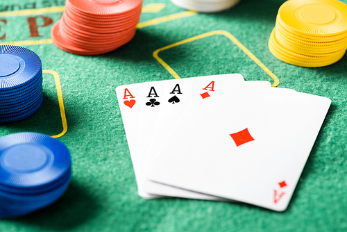 selective focus of green poker table with four aces playing cards and chips