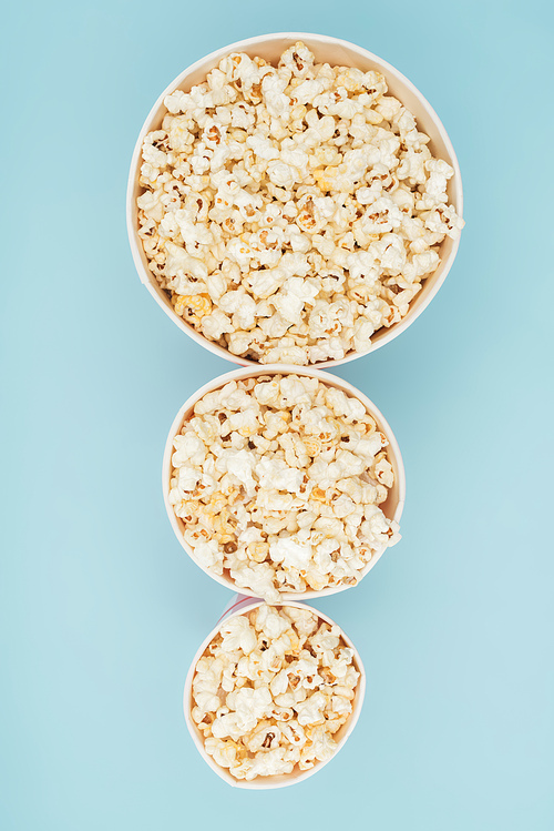 top view of popcorn buckets of different sizes in vertical row isolated on blue