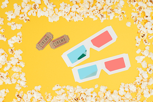 cinema tickets and 3d glasses in frame made of tasty popcorn isolated on yellow