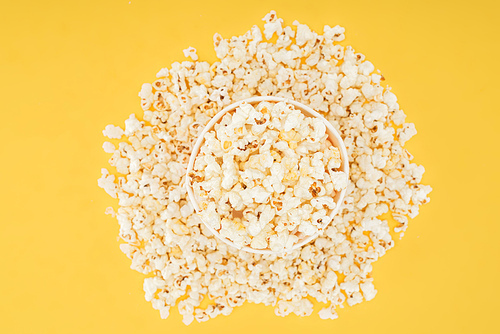 top view of carton bucket and scattered popcorn isolated on yellow
