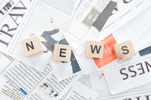 elevated view of wooden cubes with word news on newspapers