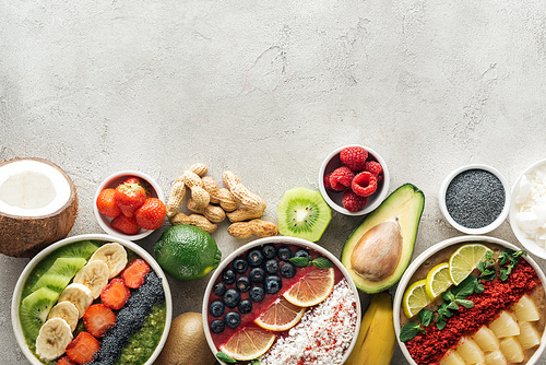 top view of healthy smoothie bowls with ingredients on grey background