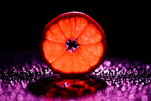 slice of grapefruit on black background with red backlit and bokeh