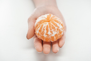 cropped view of woman holding ripe whole peeled tangerine on white background