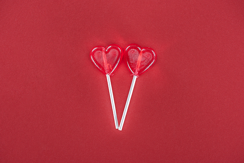 two heart shaped lollipops on red background, valentines day concept