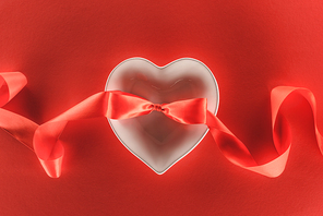 elevated view of heart symbol and festive ribbon isolated on red, st valentine day concept