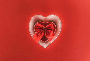 top view of heart shaped present box and festive ribbon isolated on red, st valentine day concept