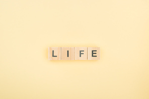 top view of life lettering made of wooden cubes on yellow background