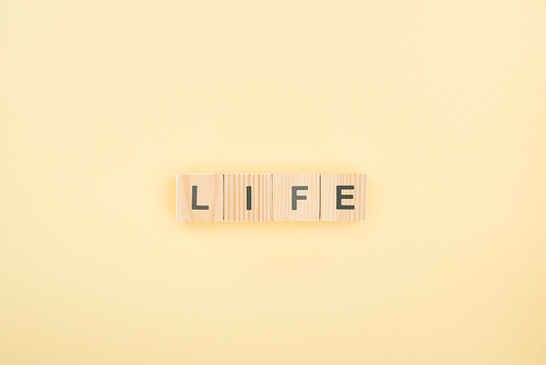 top view of life lettering made of wooden cubes on yellow background