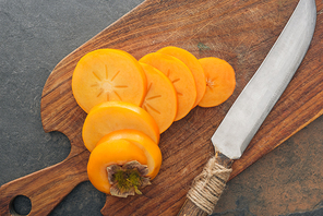 top view of persimmons slices on cutting board with knife