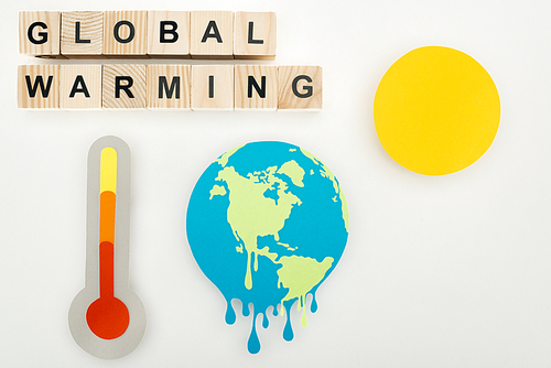 paper cut melting earth and sun, thermometer with high temperature indication on scale, and wooden cubes with global warming lettering on grey background