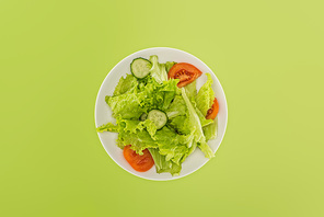 top view of chopped salad on white plate isolated on green
