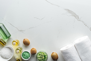 top view of different natural ingredients for handmade cosmetics, towels and cosmetic bottles on white surface