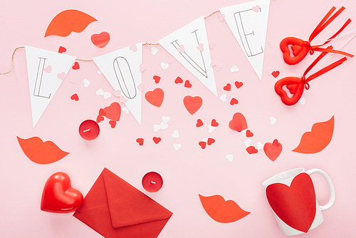 top view of valentines decorations and paper garland with 'love' lettering isolated on pink, st valentines day concept