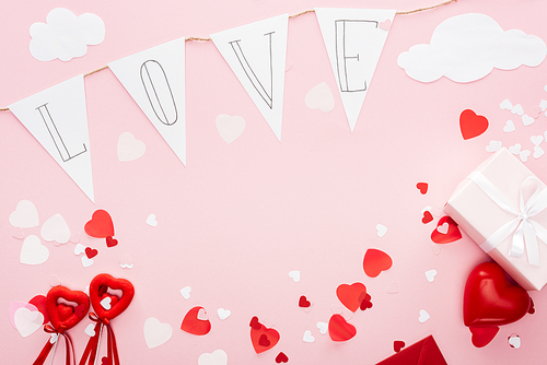 top view of valentines decorations and paper garland with 'love' lettering isolated on pink with copy space, st valentines day concept