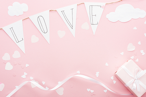 top view of paper garland with 'love' lettering and gift box isolated on pink, st valentines day concept
