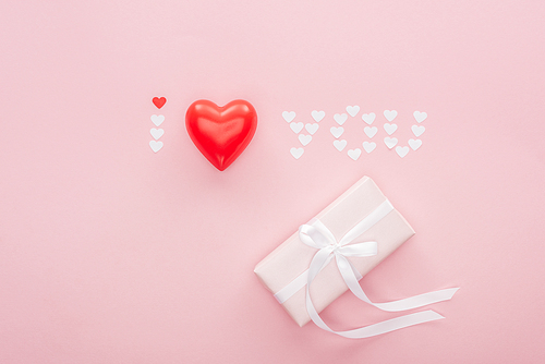 top view of gift box and 'i love you' lettering made of paper hearts isolated on pink, st valentines day concept