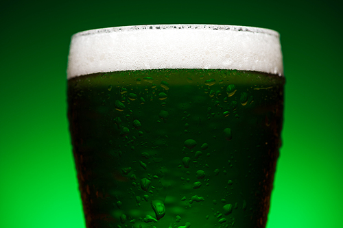 close up of glass of green irish ale isolated on green