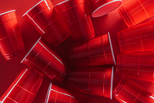top view of bright and colorful plastic cups on red background