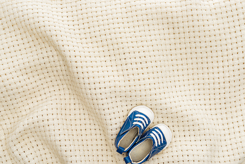 top view of blue sneakers on beige blanket with copy space