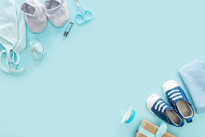 top view of scissors, pacifiers, gift, sneakers, bonnet, booties, hat on blue background