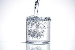 water pouring in glass on white background with back light and copy space