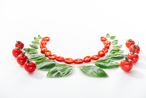 flat lay with cut chili peppers, basil leaves and ripe cherry tomatoes on white background