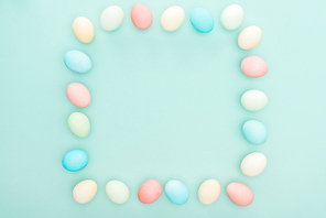 top view of empty frame made of pastel easter eggs isolated on blue