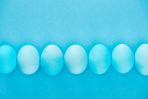 top view of blue easter eggs in row isolated on blue
