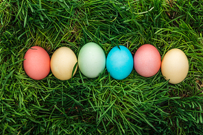 top view of colorful easter eggs in row on green grass