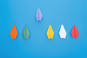 Flat lay with colorful paper planes on blue surface